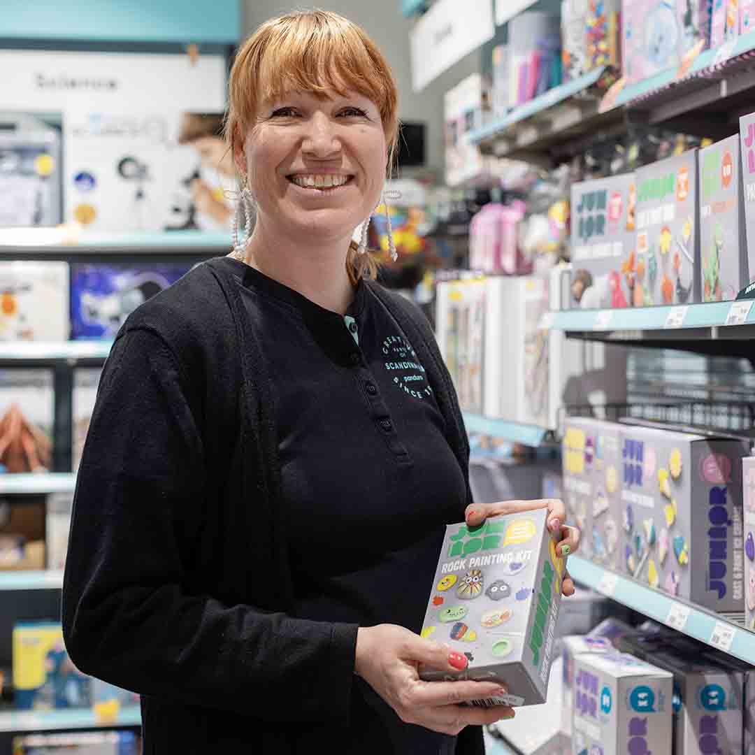 Smiling employee from Panduro holding a painting kit.